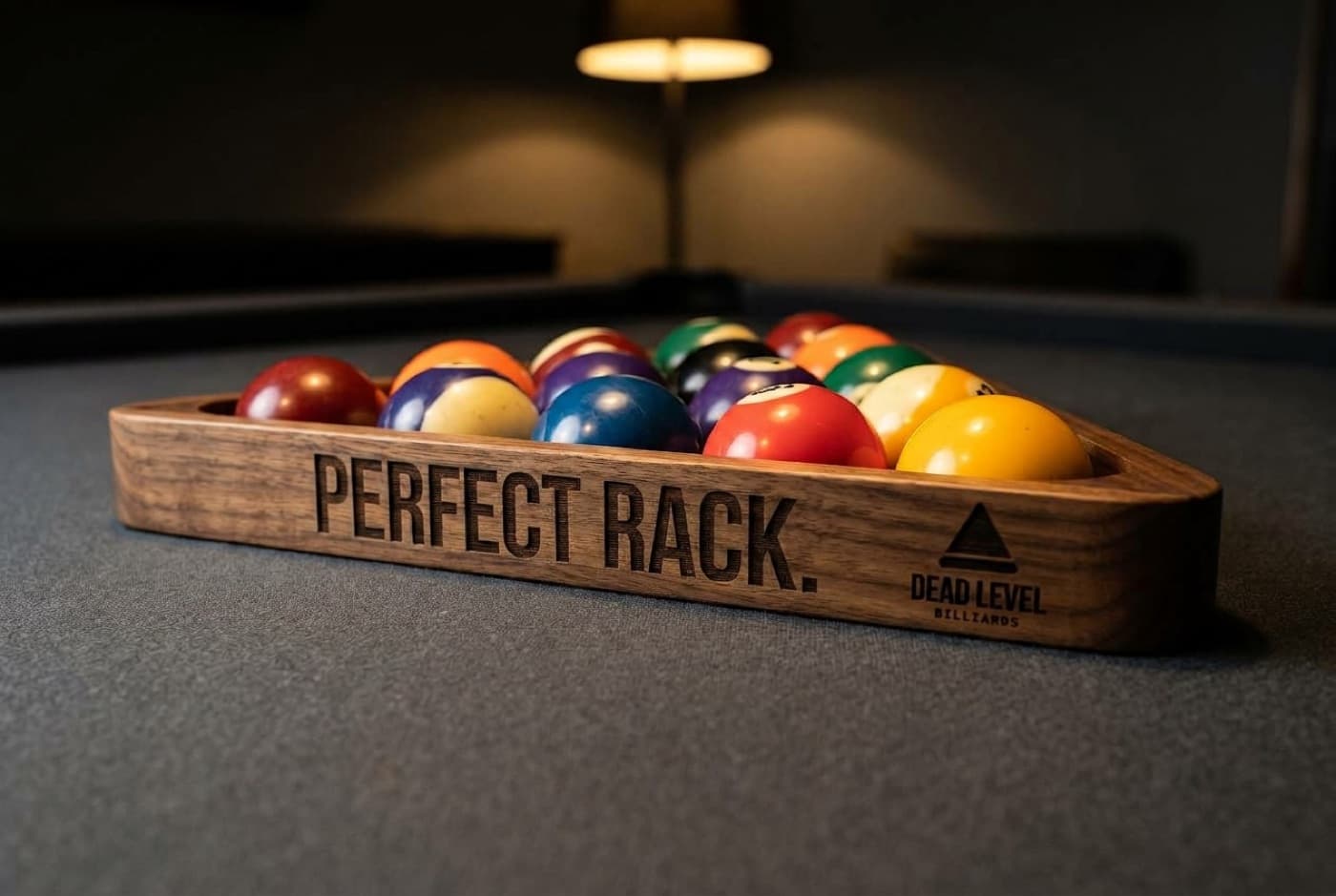 An engraved walnut rack full of balls on a pool table